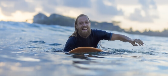 Mann mit einer Auslandsreise Krankenversicherung am surfen.
